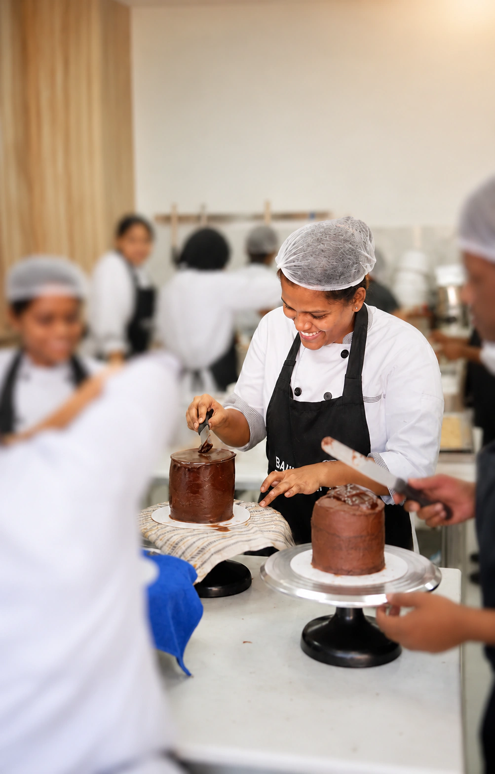 Ranjani Ganesan decorating a chocolate cake during professional bakery training